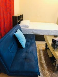 - un canapé bleu dans une chambre avec un lit dans l'établissement Premium Furnished studio, à Charjah