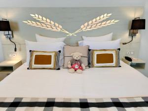 a teddy bear sitting on a bed with pillows at Hotel Beaucour in Strasbourg