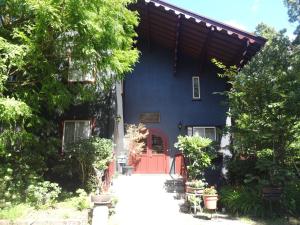 a blue house with a red door and trees at IZUNA INN & SPA - the veggie delights in Ito