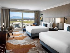 a hotel room with two beds and a large window at Fairmont Vancouver Airport In-Terminal Hotel in Richmond