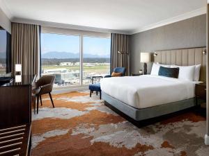 a hotel room with a bed and a large window at Fairmont Vancouver Airport In-Terminal Hotel in Richmond