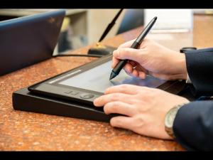 a person holding a pen in front of a laptop computer at Sanco Inn Kuwana Ekimae in Kuwana