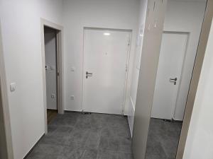 a hallway with white doors and a tile floor at Apartman AURA self CHECK-IN, FREE PRIVATE PARKING in Osijek