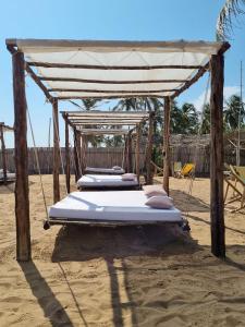 3 camas en un dosel en una playa en Hotel Bariba playa, en Cotonou