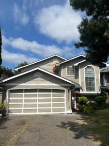 a house with a white garage door at Vancouver Airport Cozy room 舒适小屋, Richmond,near YVR in Richmond