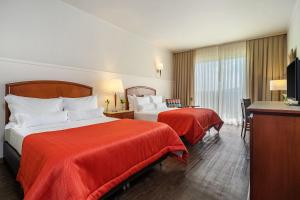 a hotel room with two beds with red sheets at Bourbon Resort Atibaia in Atibaia