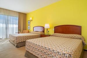 two beds in a hotel room with yellow walls at Bourbon Resort Atibaia in Atibaia