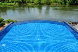 a large blue swimming pool next to a river at Princess River Kwai Hotel in Kanchanaburi City