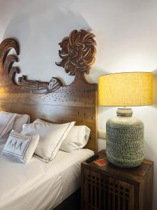 a bed with a wooden headboard and a lamp on a table at Gar Anat Hotel Boutique in Granada