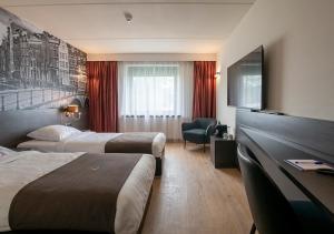 ein Hotelzimmer mit 2 Betten und einem Flachbild-TV in der Unterkunft Bastion Hotel Amsterdam Airport in Hoofddorp