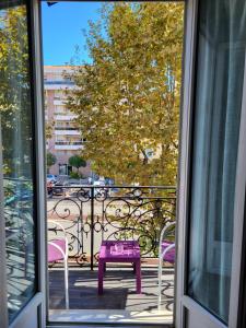 ventana con mesa púrpura y sillas en el balcón en Hotel Parisien, en Menton