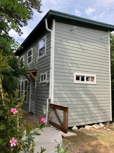 a gray house with a porch and two windows at Cozy Coop Casita - Lake Travis-Hot Tub-Tiny House in Austin