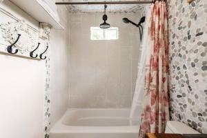 a bathroom with a tub and a shower curtain at Cozy Coop Casita - Lake Travis-Hot Tub-Tiny House in Austin