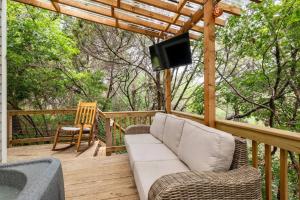 a porch with a couch and a television on a deck at Cozy Coop Casita - Lake Travis-Hot Tub-Tiny House in Austin