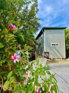 a house with a building and flowers in front of it at Cozy Coop Casita - Lake Travis-Hot Tub-Tiny House in Austin