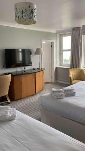 a hotel room with two beds and a flat screen tv at Best Western Plus Citrus Hotel Eastbourne in Eastbourne