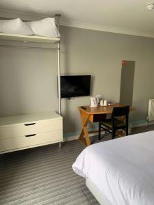 a bedroom with a bed and a desk and a bed and a bed at Best Western Plus Citrus Hotel Eastbourne in Eastbourne