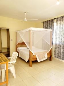 - une chambre avec un lit à baldaquin et une table dans l'établissement Casuarina Lounge, à Malindi