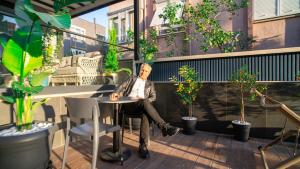 a man sitting at a table on a balcony with potted plants at Stile Suite Marine Hotel in Antalya