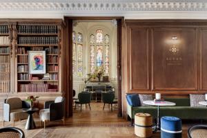 a library with a green couch and a stained glass window at Palacio Arriluce Hotel in Getxo