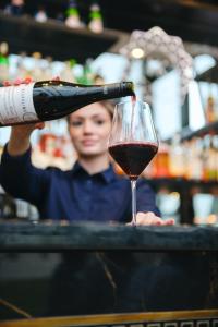 une femme versant une bouteille de vin dans un verre de vin dans l'établissement Hotel Keflavik by Reykjavik Keflavik Airport, à Keflavík