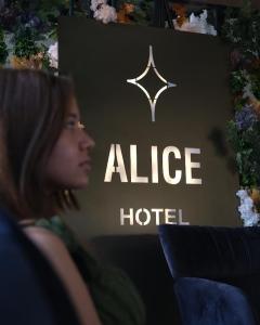 kobieta siedząca przed ładnym znakiem hotelowym w obiekcie Alice Hotel Antalya w Larze