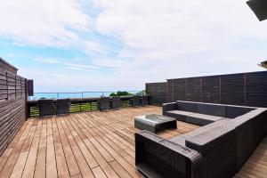 a patio with a couch and chairs on a deck at 伊豆高原 記念日を祝う宿 自然家 Haco しぜんや ハコ in Ito