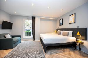 - une chambre avec un lit, un canapé et une chaise dans l'établissement Staycity Aparthotels Edinburgh West End, à Édimbourg