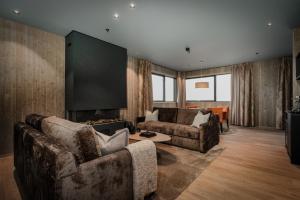 a living room with two couches and a flat screen tv at Pellestova Hotell Hafjell in Hafjell