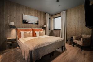 a bedroom with a large bed and a chair at Pellestova Hotell Hafjell in Hafjell