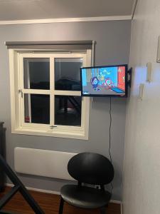 a tv on a wall with a chair and a window at Comfortable Villa In Lillehammer in Lillehammer