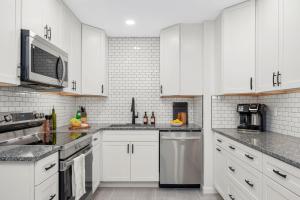 a kitchen with white cabinets and stainless steel appliances at Retro Revival - Mid-Century Refuge with a '70s Twist in Alachua