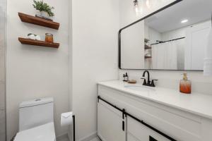 a white bathroom with a sink and a mirror at Retro Revival - Mid-Century Refuge with a '70s Twist in Alachua