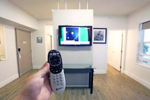 a person holding a remote control in front of a tv at South of Fifth Studio Steps to Beach on Ocean Drive in Miami Beach