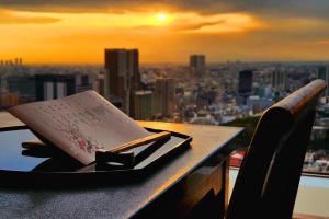 un libro sobre una mesa con vistas a la ciudad en Shinagawa Prince Hotel, en Tokio