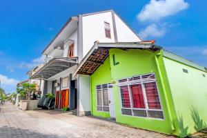 een groen en wit gebouw op een straat bij OYO 94364 Dalinah Homestay in Yogyakarta