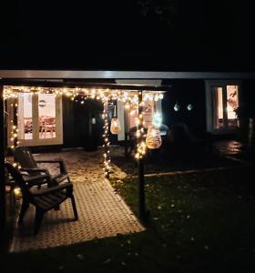 a patio with lights and a chair in the dark at Stayatsas Tiny House Julia in de bossen op de Veluwe! in Epe