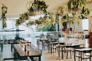 een restaurant met houten tafels, stoelen en planten bij PULANG ke UTTARA in Yogyakarta