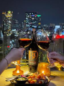 2 persone che tengono bicchieri di vino su un tavolo di Happy Life Grand Hotel & Rooftop Skybar ad Ho Chi Minh