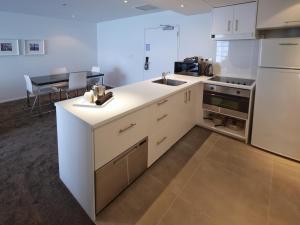 a kitchen with white cabinets and a white refrigerator at Quest Parnell Serviced Apartments in Auckland