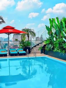 una piscina sul tetto di un edificio con ombrellone rosso di Happy Life Grand Hotel & Rooftop Skybar ad Ho Chi Minh