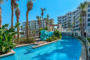 a swimming pool with blue chairs and palm trees at Destin West Gulfside #203 in Fort Walton Beach