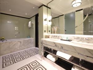 a bathroom with two sinks and a tub and a large mirror at The Beaumont Mayfair in London