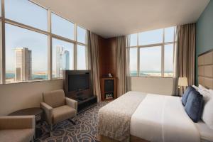 una camera con letto, TV e finestre di Ramada Abu Dhabi Corniche a Abu Dhabi