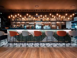 un bar avec six chaises devant un comptoir dans l'établissement Novotel Chartres, à Chartres