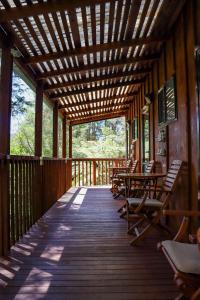 a wooden deck with chairs and tables on it at Kanuka Ridge Lodge in Marahau