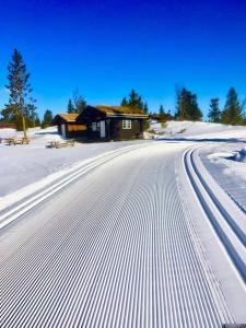 a snow covered road in front of a house at Apartment with Electric car charger ski in out in Sjusjøen