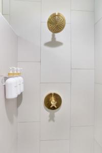 a white bathroom with a toilet and a gold button at The Poe - Stylish Studio in downtown High Springs in High Springs