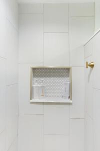 a white tiled bathroom with white appliances on a shelf at The Poe - Stylish Studio in downtown High Springs in High Springs