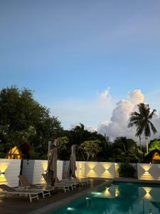 una piscina con tumbonas y sombrillas en Found Mansion, en Pantai Cenang